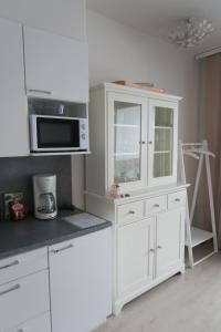 a kitchen with white cabinets and a microwave at Ihana yksiö Kangasalan Harjunsalossa in Kangasala