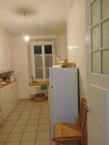 cocina con nevera blanca y silla en JIMOBA PLACE, en La Chaux-de-Fonds
