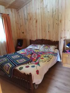 1 dormitorio con 1 cama con pared de madera en Cabañas la Playa, en Isla Negra