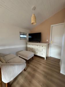a living room with a couch and a tv at Le Lodge de l'océan - Maison familiale en bois neuve - Piscine chauffée in Biscarrosse