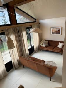 a living room with a couch and some windows at Le Lodge de l'océan - Maison familiale en bois neuve - Piscine chauffée in Biscarrosse +49 photos