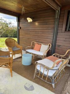 a patio with wicker chairs and a table at Le Lodge de l'océan - Maison familiale en bois neuve - Piscine chauffée in Biscarrosse