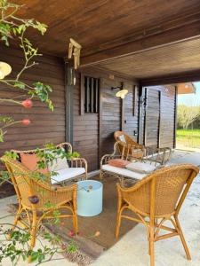 a patio with wicker chairs and a table at Le Lodge de l'océan - Maison familiale en bois neuve - Piscine chauffée in Biscarrosse