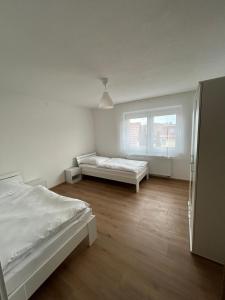 a white bedroom with two beds and a window at Ferienwohnungen in Heidenheim in Heidenheim an der Brenz