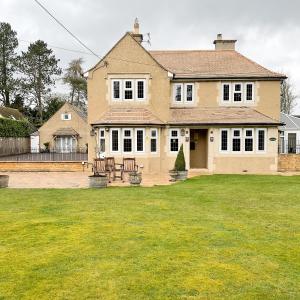 una grande casa con un prato davanti di Southlands B&B a Bourton on the Water