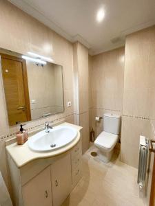 een badkamer met een wastafel, een toilet en een spiegel bij Apartamento Nuskis in Porriño