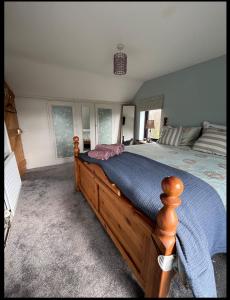 a bedroom with a wooden bed with a blue comforter at Seaview House Reenard South in Cahersiveen