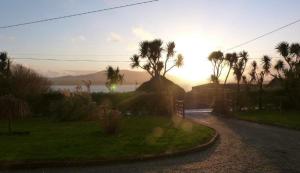 a sunset over a street with palm trees and a road at Seaview House Reenard South in Cahersiveen