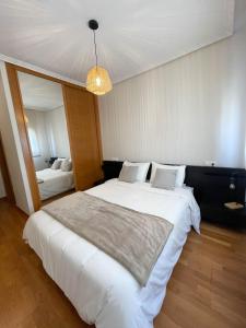 een slaapkamer met een groot wit bed en een spiegel bij Apartamento Nuskis in Porriño