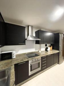 een keuken met roestvrijstalen apparatuur en zwarte kasten bij Apartamento Nuskis in Porriño