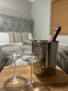 two wine glasses sitting on a wooden table with a bucket at Hansen@15 Self Catering Studio in Piet Retief