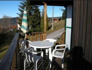 una mesa y sillas en un porche con mesa y sillas en Le P'tit Caribou, près des pistes, en Gérardmer