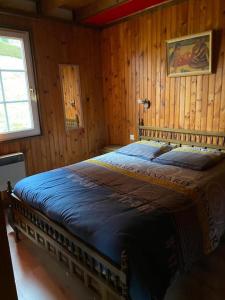 una camera da letto con un grande letto in una camera in legno di Le P'tit Caribou, près des pistes a Gérardmer