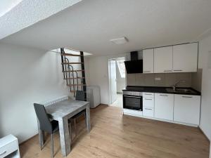 a kitchen with white cabinets and a table and a staircase at Ferienwohnungen in Heidenheim in Heidenheim