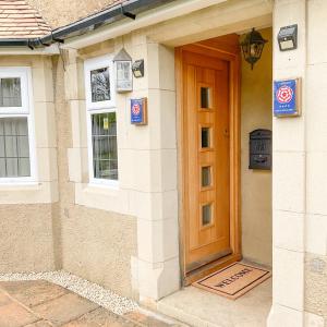 una casa con una porta di legno sul lato di Southlands B&B a Bourton on the Water