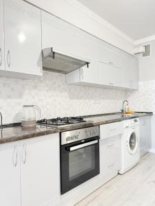 a white kitchen with a stove and a dishwasher at Gio Apartment in Chişinău