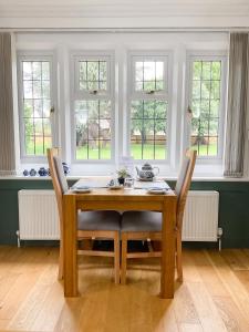 a dining room with a wooden table and windows at Southlands B&B in Bourton on the Water +10 photos