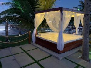 a bed with a canopy in a resort with palm trees at Casa de praia Itamaracá - Pontal da Ilha in Itamaracá +76 photos