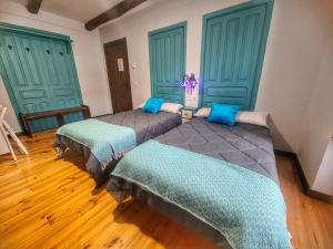2 camas en una habitación con puertas verdes en Albergue El Encanto en Villares de Órbigo
