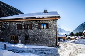 een stenen huis met sneeuw op het dak bij Résidence La Ferme A Roger - 4 Pièces pour 8 Personnes 434 in Chamonix-Mont-Blanc