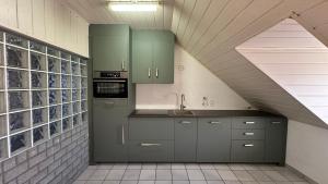 une cuisine avec des placards gris et un toit incliné dans l'établissement LinZn vakantiehuis, à Wuustwezel