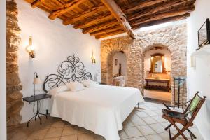 1 dormitorio con cama blanca y pared de piedra en Agroturismo Can Gall, en Sant Llorenç de Balàfia