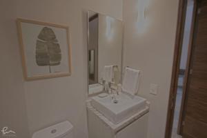 a white bathroom with a sink and a mirror at The Gallery Condos Playa de Carmen in Playa del Carmen
