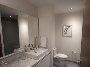 a white bathroom with a sink and a toilet at The Gallery Condos Playa de Carmen in Playa del Carmen