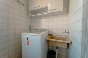 uma pequena casa de banho com uma máquina de lavar roupa e um lavatório em Apartamento 3 Quartos Central com Ar SQ41 em Maringá