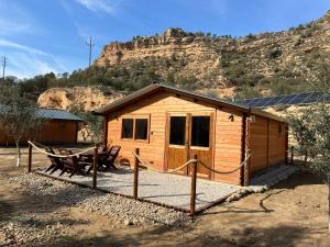 a small wooden cabin with a bench and a mountain at Big Fish River Ebro Resort in Riba-roja d'Ebre