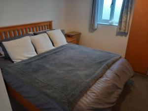 a bedroom with a bed with a blue blanket and a window at Remarkable 2-Bed Apartment near Bognor beaches in Bognor Regis