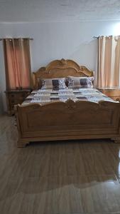 Villas in A Gated Community في May Pen: سرير خشبي كبير في غرفة نوم وأرضيات خشبية