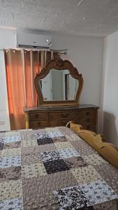 a bedroom with a dresser and a bed with a mirror at Villas in A Gated Community in May Pen