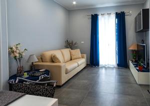 a living room with a couch and blue curtains at NIKA NIKA Holiday House in Carini