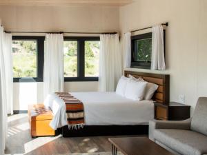 a bedroom with a bed and a chair and windows at Ofland Escalante in Escalante +29 photos