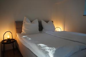 a bed with white sheets and pillows in a room at Schwalbennest in Mechernich