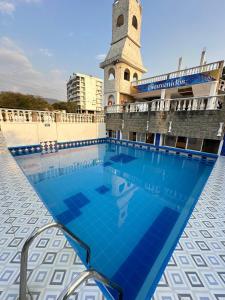 a swimming pool in front of a building with a clock tower at SGH Castillo Aqua in Santa Marta
