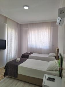 two beds in a hotel room with a tv at VİLLA BELİNAY in Belek