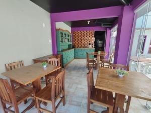 uma cozinha com mesas e cadeiras de madeira e paredes roxas em Pousada Casa da Maga - Centro em Blumenau