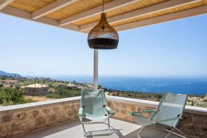two chairs on a balcony with a view of the ocean at Patio Villas Complex in Stoupa