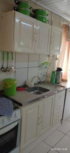 uma pequena cozinha com armários brancos e um lavatório em Casa Gralha Azul em Lages