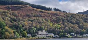 a house on the side of a hill next to the water at Loch Long Hotel in Arrochar