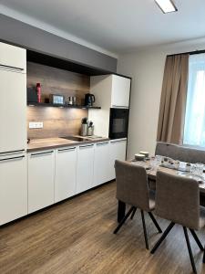 a kitchen with white cabinets and a table and chairs at Harmony Living - Graz Stadion Liebenau in Graz