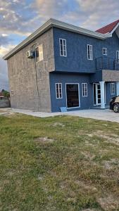 Villas in A Gated Community في May Pen: مبنى أزرق كبير مع مرآب للسيارات