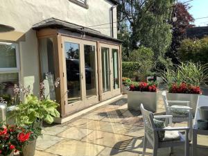 a garden room with plants and flowers on a patio at Time House Cottage in Huby
