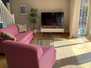 a living room with two pink couches and a tv at Time House Cottage in Huby