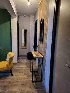 einen Flur mit einem Tisch und einem gelben Stuhl in der Unterkunft Appartement rénové in Leffrinckoucke