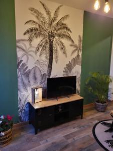 ein Wohnzimmer mit einem Palmenmilch an der Wand in der Unterkunft Appartement rénové in Leffrinckoucke