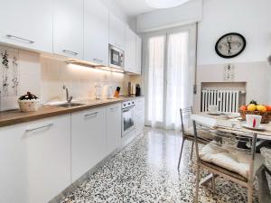 een witte keuken met een tafel en een klok aan de muur bij A casa di Ezio e Paola in La Spezia