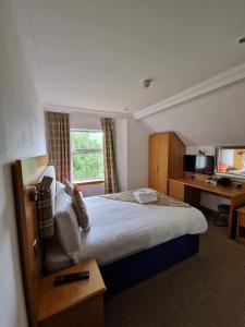 a bedroom with a bed with a desk and a window at Loch Long Hotel in Arrochar
